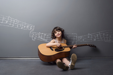 enfant 6 ans apprenant la guitare en souriant