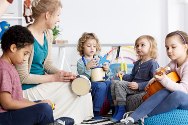 cours eveil musical avec professeure et 4 enfants jouant du tambourin et de la guitare