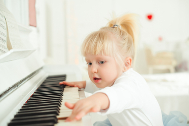 jeune enfant apprenant le piano en s'amusant