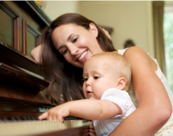 bébé joue du piano avec sa maman heureuse
