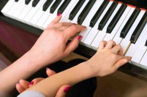 professeur piano enseigne main enfant pianiste