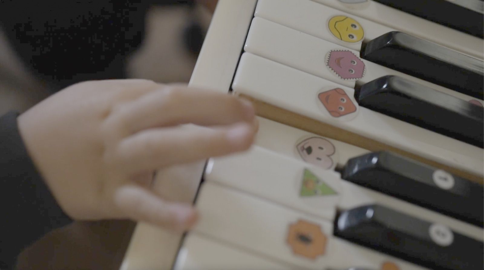 Doigts d’un enfant sur un clavier de piano avec des gommettes de couleur