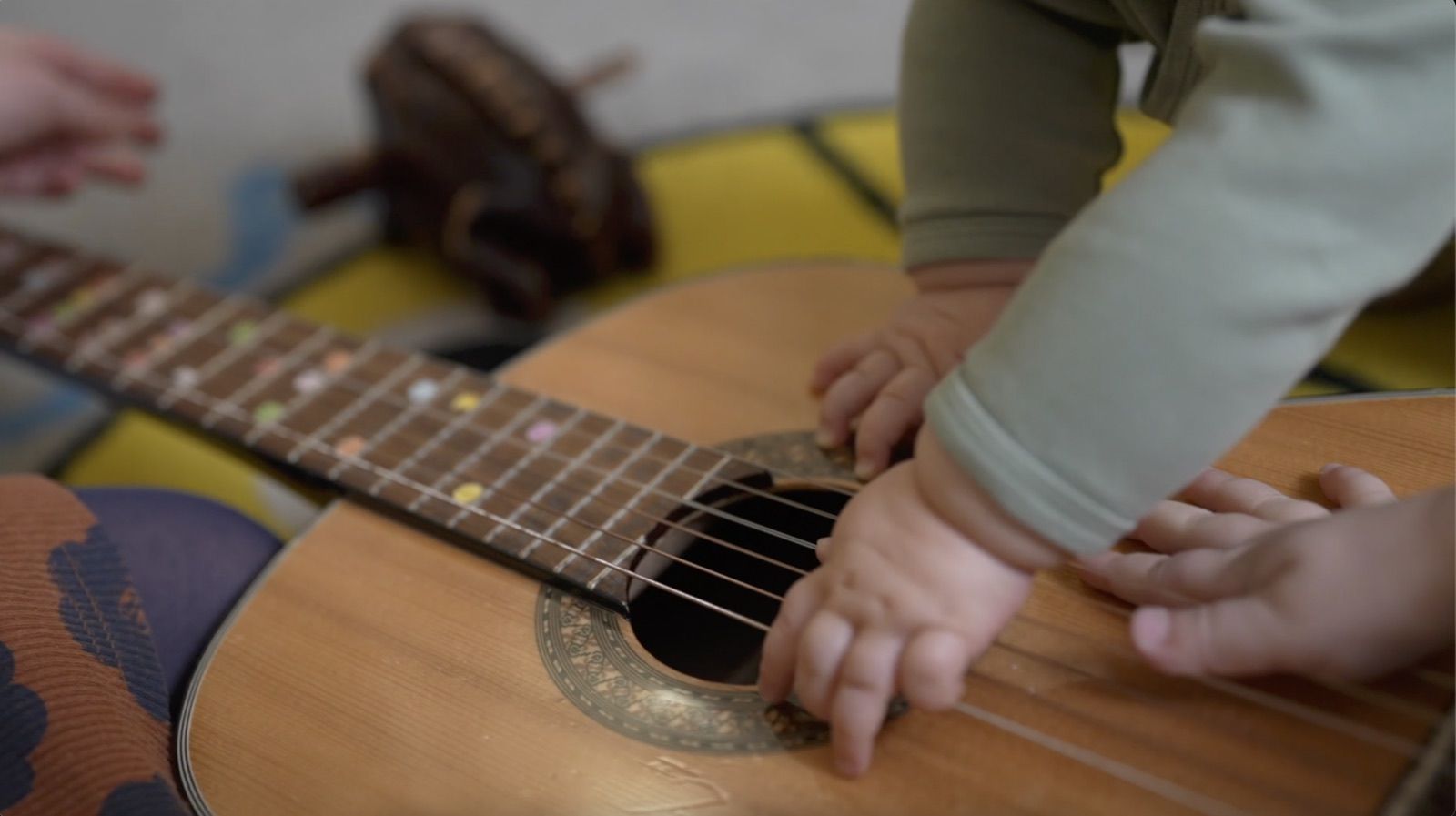 Mains d’un bébé sur une guitare pendant un atelier d’éveil musical à Paris 11